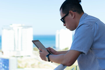 Young man working on his tablet while standing on the bench at home