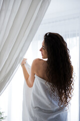 Nice woman standing next to the window, body shape 