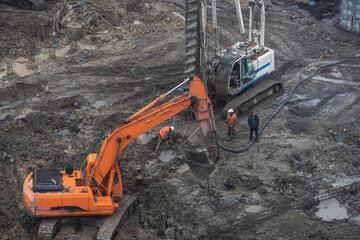 Wheel loader Excavator with backhoe unloading sand at eathmoving works in construction site.