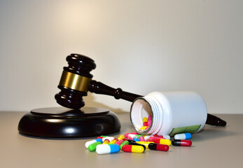 Mallet of judge and Multicolored pills in capsules in courtroom. Litigation Medicine-Related...