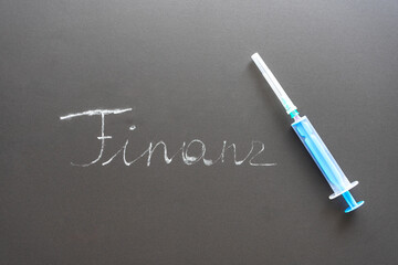 Finanzen mit Kreide geschrieben in Deutsch und eine Spritze auf einer Tafel. Wort Symbol,...