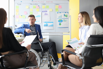 Business coach in wheelchair conducts business meeting of employees