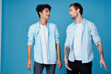 two friends in an unbuttoned shirt and in white t-shirts on a blue background gesturing with hands cropped view party 