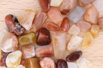 Red silk jade jewel stones heap up texture on light varnished wood background