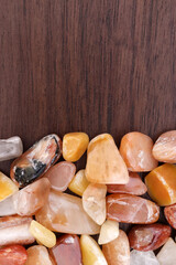 Red silk jade heap jewel stones texture on half brown varnished wood background. Place for text.