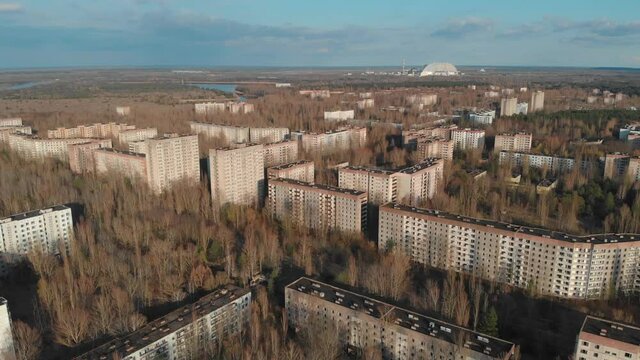 View of ghost city of Pripyat with Chernobyl nuclear power plant and sarcophagus on background. 35 years after disaster and evacuation. Traveling during pandemic of Covid-19