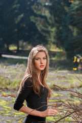 Fototapeta premium Portrait of a girl in an autumn park against a background of yellow foliage. Blurred background. Selective focus.