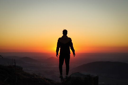 Silhouette of a young athlete who stands on a tree stump and is surrounded by a pounding ball of the setting sun. Add confidence. Ondrejnik, Beskydy mountains, czech republic