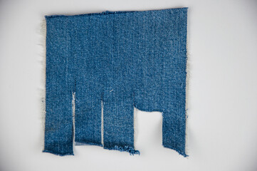 Fototapeta premium Destroyed torn denim blue jeans frayed flap patch fabric frame on white background