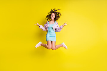 Fototapeta na wymiar Full size photo of happy funky funny crazy girl jumping showing tongue rock'n'roll sign isolated on yellow color background