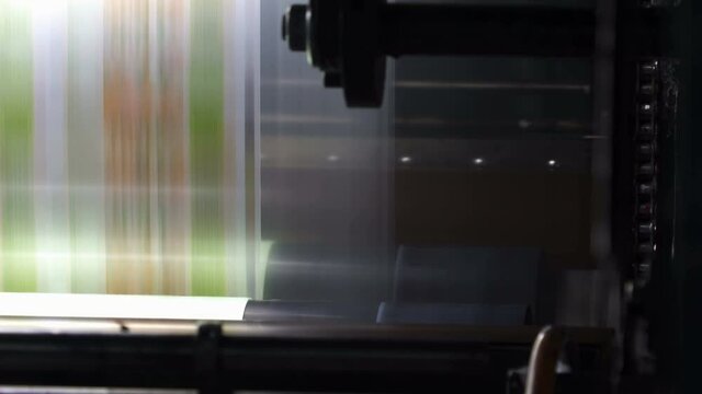 Printing house. Printing on film. The shafts rotate. Anilox. Flexo printing. Film quickly between the shafts. Printing Machine