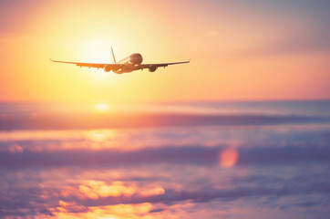 Fototapeta na wymiar Airplane flying over tropical beach with smooth wave and sunset sky abstract background.