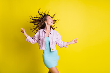 Portrait of lovely dreamy cheerful wavy-haired girl dancing having fun copy space isolated over bright yellow color background