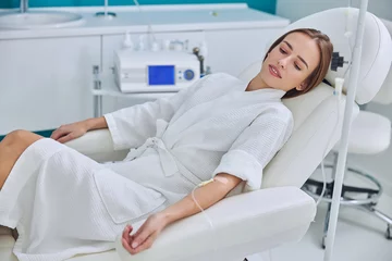 Fotobehang Redheaded beautiful female resting and getting IV infusion in spa salon © Viacheslav Yakobchuk