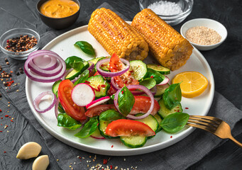 Vegetable salad and fried corn on a dark background.