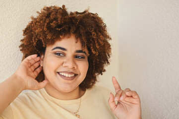 Beautiful happy smiling curvy plus size African black woman afro hair with make up posing in beige t-shirt on white background. Body imperfection, body acceptance, body positive and diversity concept.