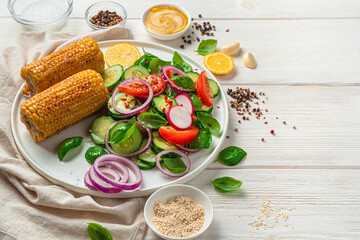 Vegetable salad with basil and sesame seeds and corn on a light background.