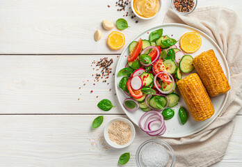 Salad with fresh vegetables, sesame and basil and fried corn on a white wooden table. Top view, copy space.
