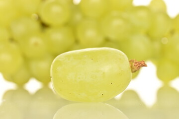 One ripe berry of sweet grapes in focus in the foreground, close-up, in the background - a bunch of grapes.