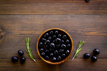 Black olives in wooden bowl. Overhead view