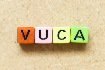 Color alphabet letter block in word VUCA (abbreviation of Volatility, uncertainty, complexity and ambiguity) on wood background