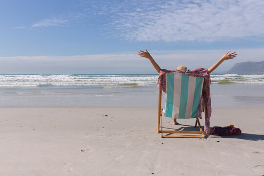 Caucasian woman wearing bikini sitting on deck chair at the beach