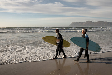 Senior african american couple carrying surf boards walking on the beach