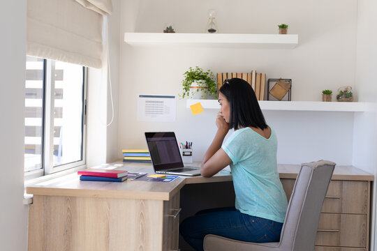 Mixed race gender fluid man working at home using laptop - Powered by Adobe