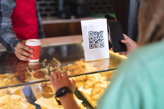 Mid section of two mixed race male taking picture of qr code and passing coffee