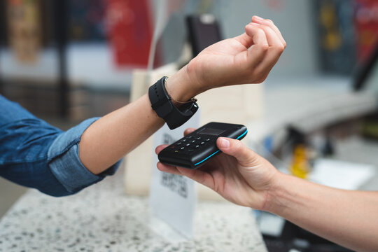 Midsection of caucasian woman making contactless watch payment over counter at gym