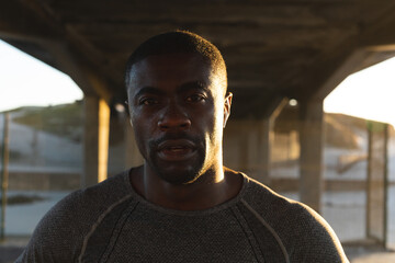 Portrait of african american man exercising outdoors on bridge at sunset