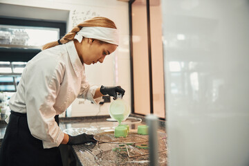 Naklejka na ściany i meble Focused woman in chef uniform making dessert