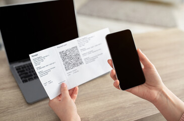 Woman using mobile phone to scan the QR code for the bill through the app, smartphone with blank screen.