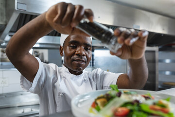 Happy african american professional chef finishing dish before serving