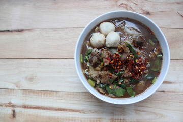 Beef noodles, top view in the bowl, Thai delicious food isolated on wooden background closeup.