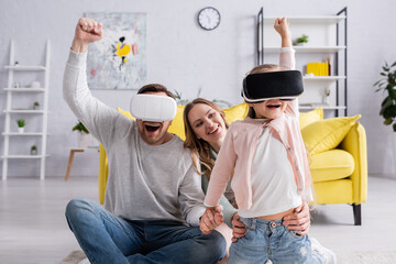 Excited girl and father using virtual reality headsets near mother at home.