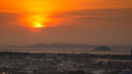 Landscape of sunset or sunrise over the city during misty or foggy day with orange color sun light.