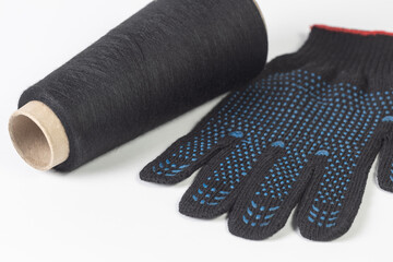 Close-up spool with black cotton thread and construction glove on white isolated background. Manufacturing and textile concept