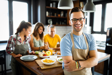 Group of happy friends having fun in kitchen, cooking food together