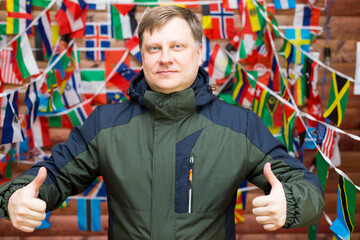 Man showing thumbs up to class on the background of a wall of flags of the world.