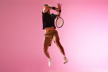 Young caucasian man playing tennis isolated on pink studio background, action and motion concept