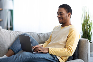 Relaxed black guy using laptop at home