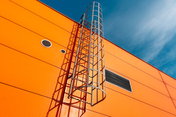 Orange industrial building wall with metal ladder © graja