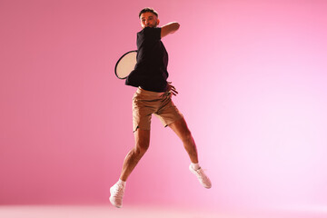 Fototapeta na wymiar Young caucasian man playing tennis isolated on pink studio background, action and motion concept