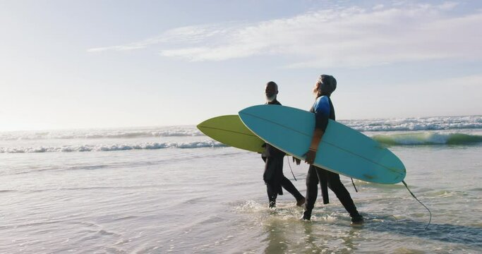 Senior African American Couple Walking With Surfboards At The Beach