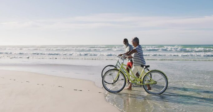 Senior african american couple walking with bicycles at the beach