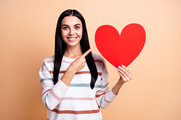 Photo of young girl happy smile indicate fingers big red paper heart ad promo advise choice isolated over beige color background