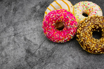 International World Donut Day. Delicious sweet donuts with icing and filling inside on a dark background. American favorite baked goods