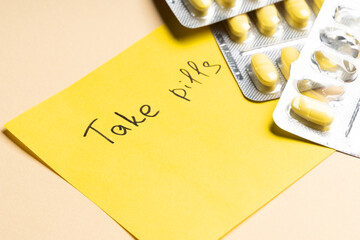 Yellow pills in blister and note to take pills on yellow background.Place for text