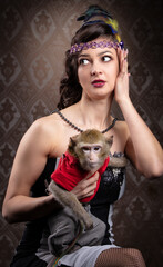 Retro female portrait in the style of 20s or 30s. A gorgeous lady is holding a little monkey.